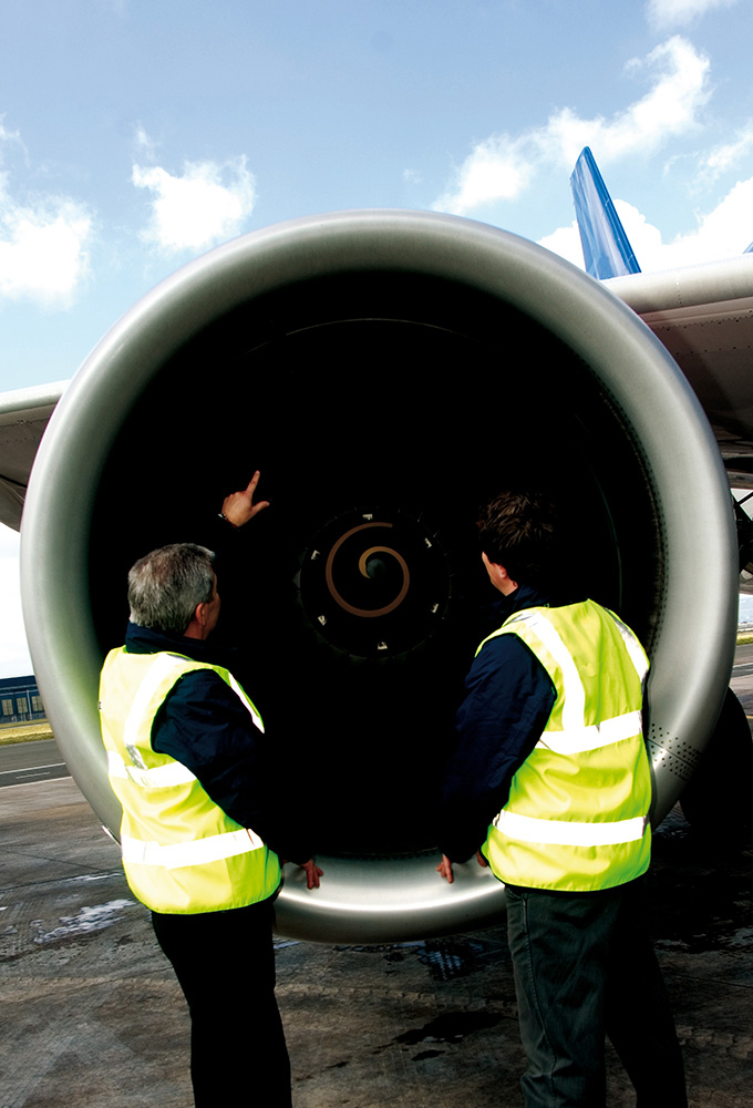 Zwei Mechaniker betrachten den Motor eines Großflugzeugs