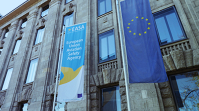 The façade of the EASA Headquarters building, with an EASA banner and a EU banner in the front.