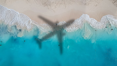 the shadow of an airplane over a light blue sea and sand